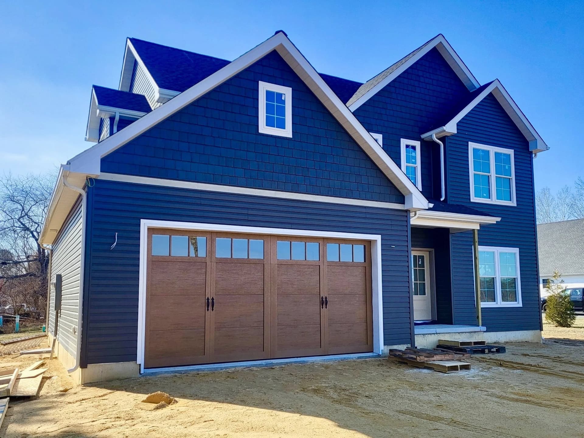 New navy-sided home with a wood-look carriage-style double garage door with window tops